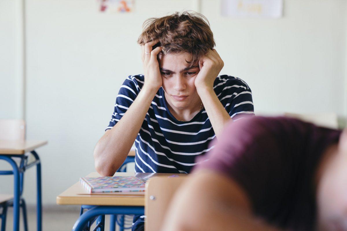 Schüler, der nachdenklich im Klassenzimmer sitzt. Grund dafür ist seine Angst, vor der beruflichen Zukunft.